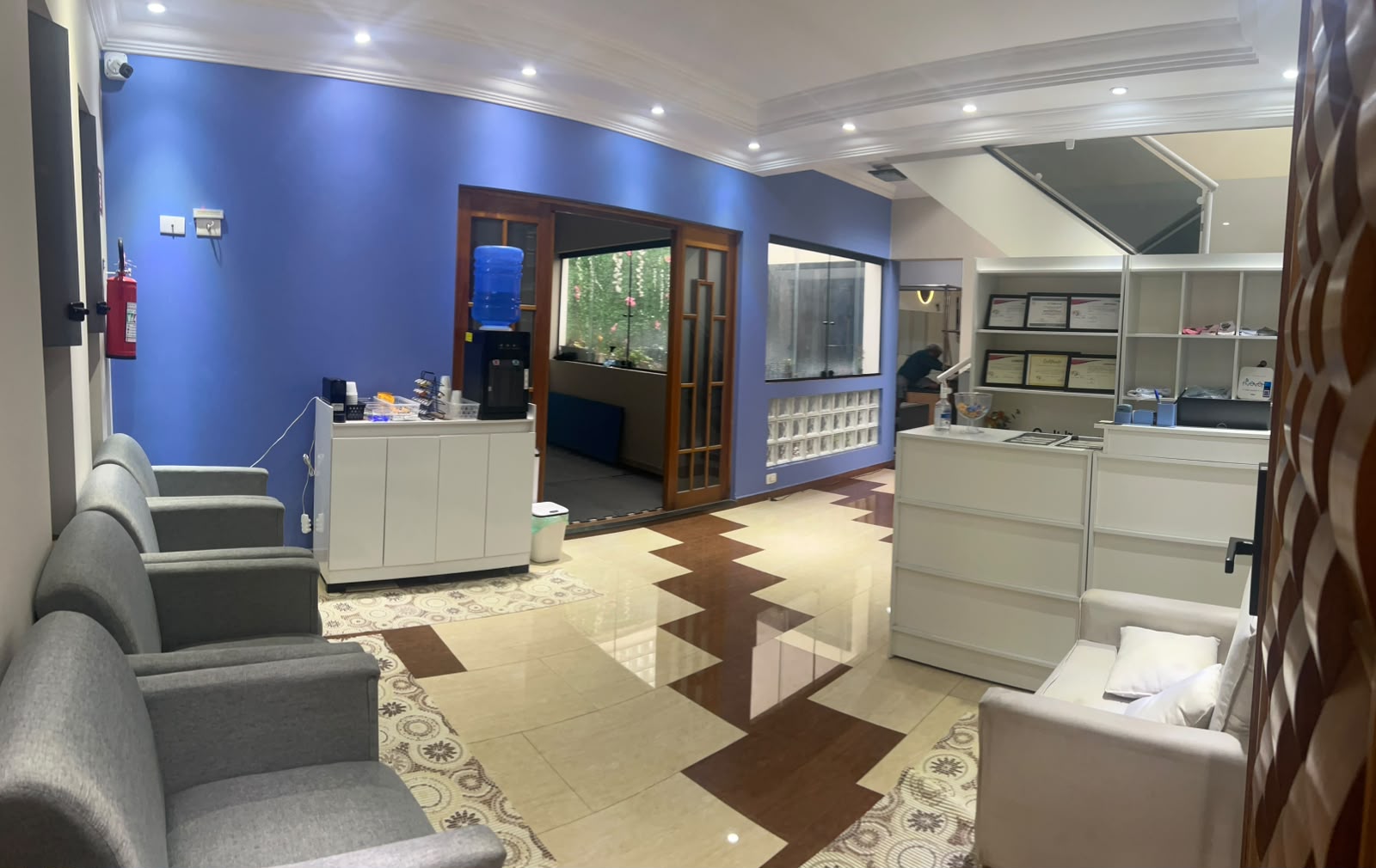 Recepção ampla e sofisticada com parede azul e balcão branco