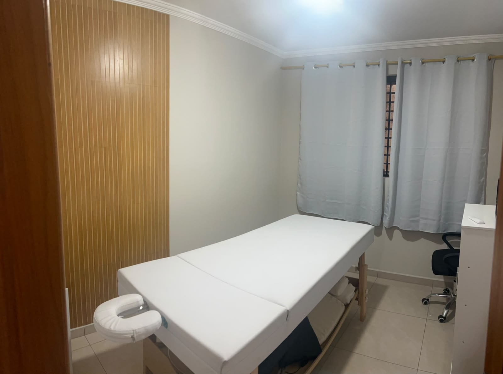 Sala privativa de atendimento com maca profissional branca e ambiente relaxante